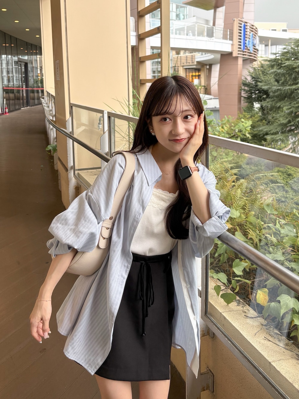 ブラック系のスカート、ブルー系のシャツ/ブラウス、ベージュ系のハンドバッグを着用したレディースの秋コーディネートの2枚目の写真