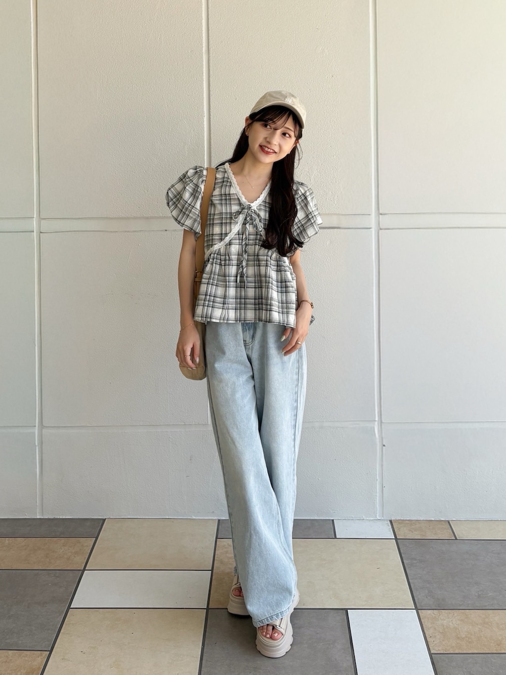 ブラック系のトップス、ベージュ系のショルダーバッグ、ブルー系のデニムパンツを着用したレディースの秋コーディネートの3枚目の写真