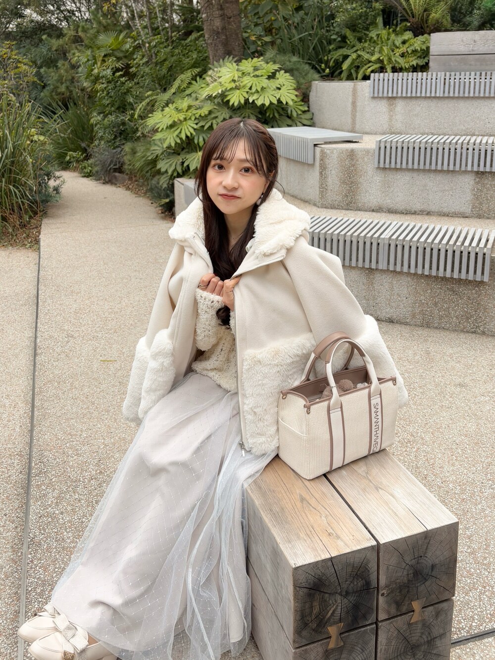 ホワイト系のワンピース、ホワイト系のハンドバッグ、ホワイト系のその他アウターを着用したレディースの冬コーディネートの2枚目の写真