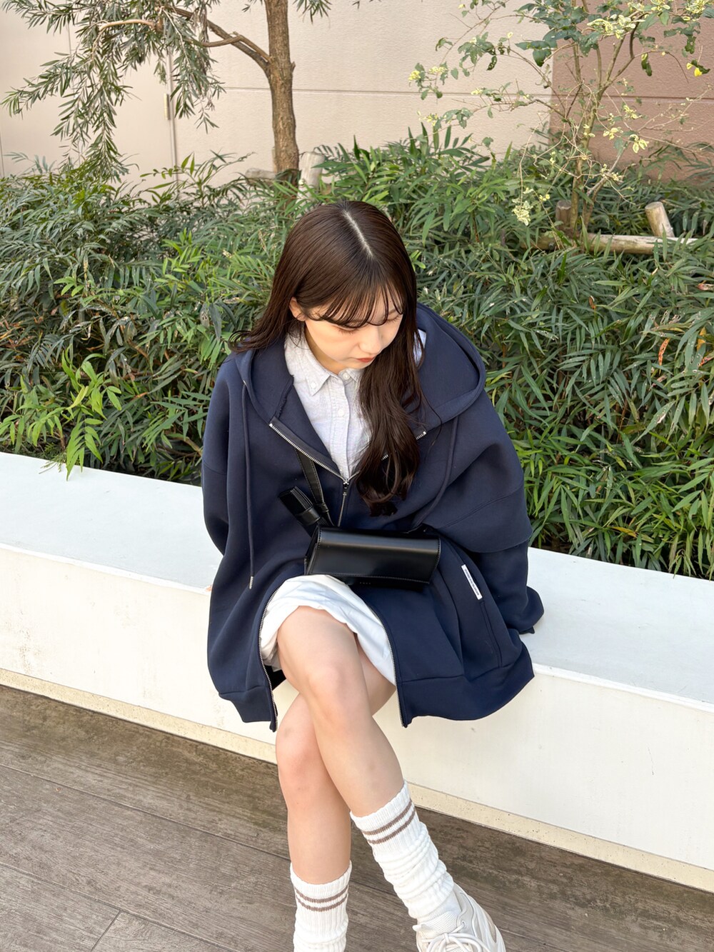 ホワイト系のスカート、ブルー系のパーカー、ブラック系のショルダーバッグを着用したレディースの春コーディネートの5枚目の写真