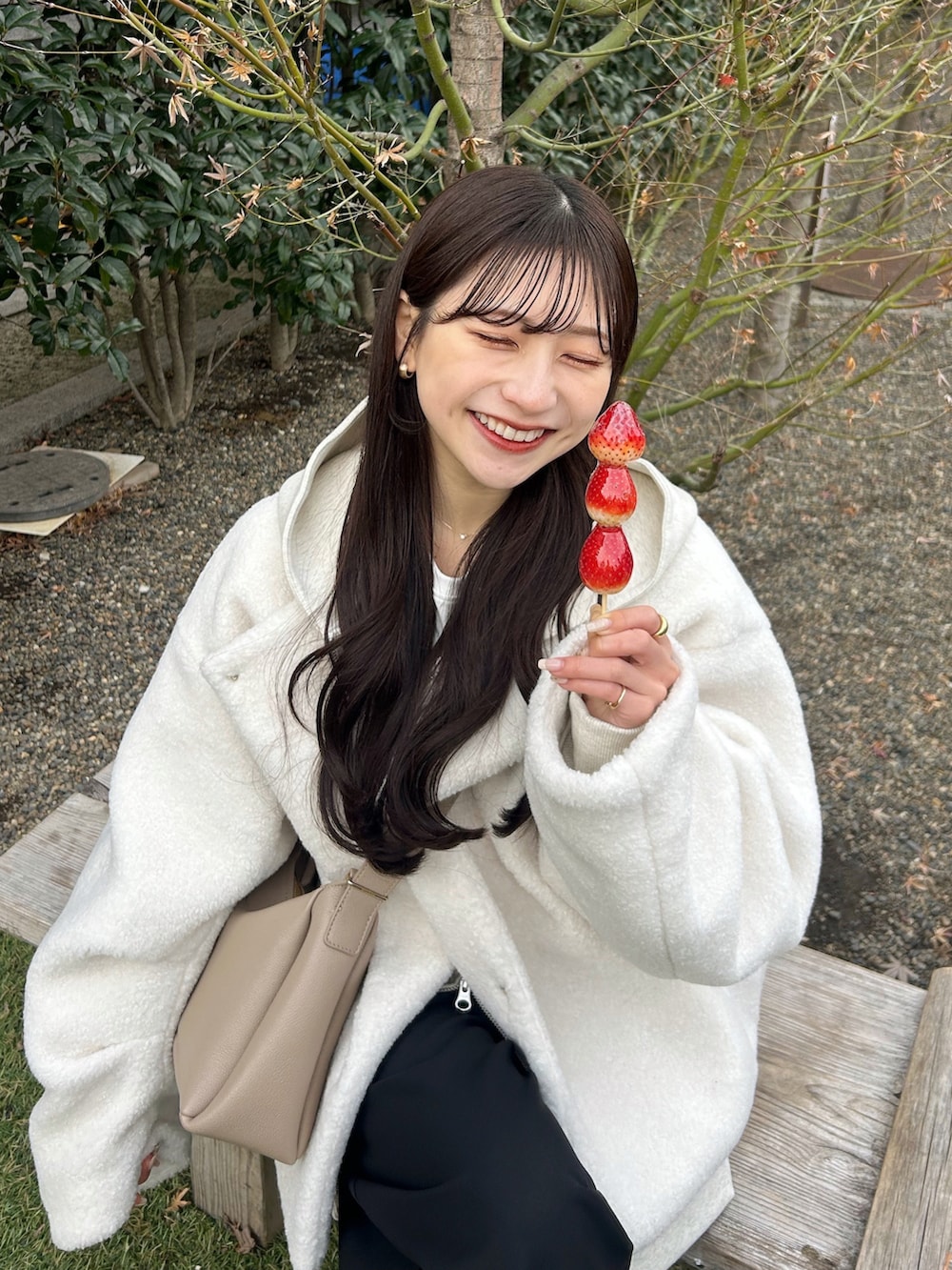 ブラック系のスラックス、ホワイト系のブルゾン、ベージュ系のバッグを着用したレディースの冬コーディネートの4枚目の写真