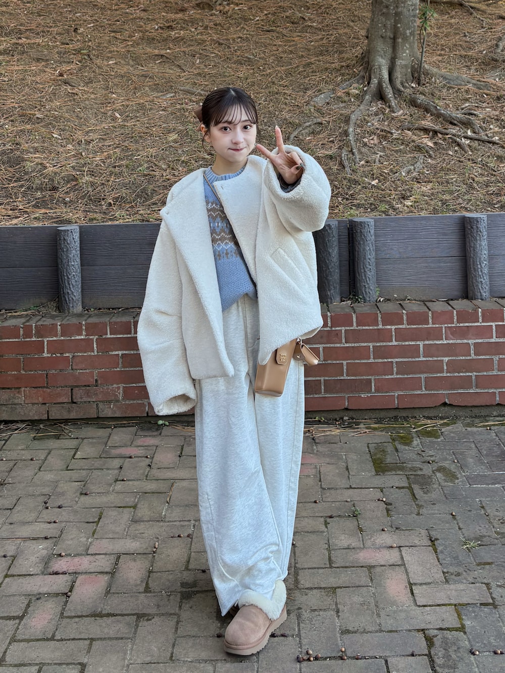 グレー系のスウェットパンツ、ホワイト系のブルゾン、ブルー系のニット/セーターを着用したレディースの冬コーディネートの2枚目の写真