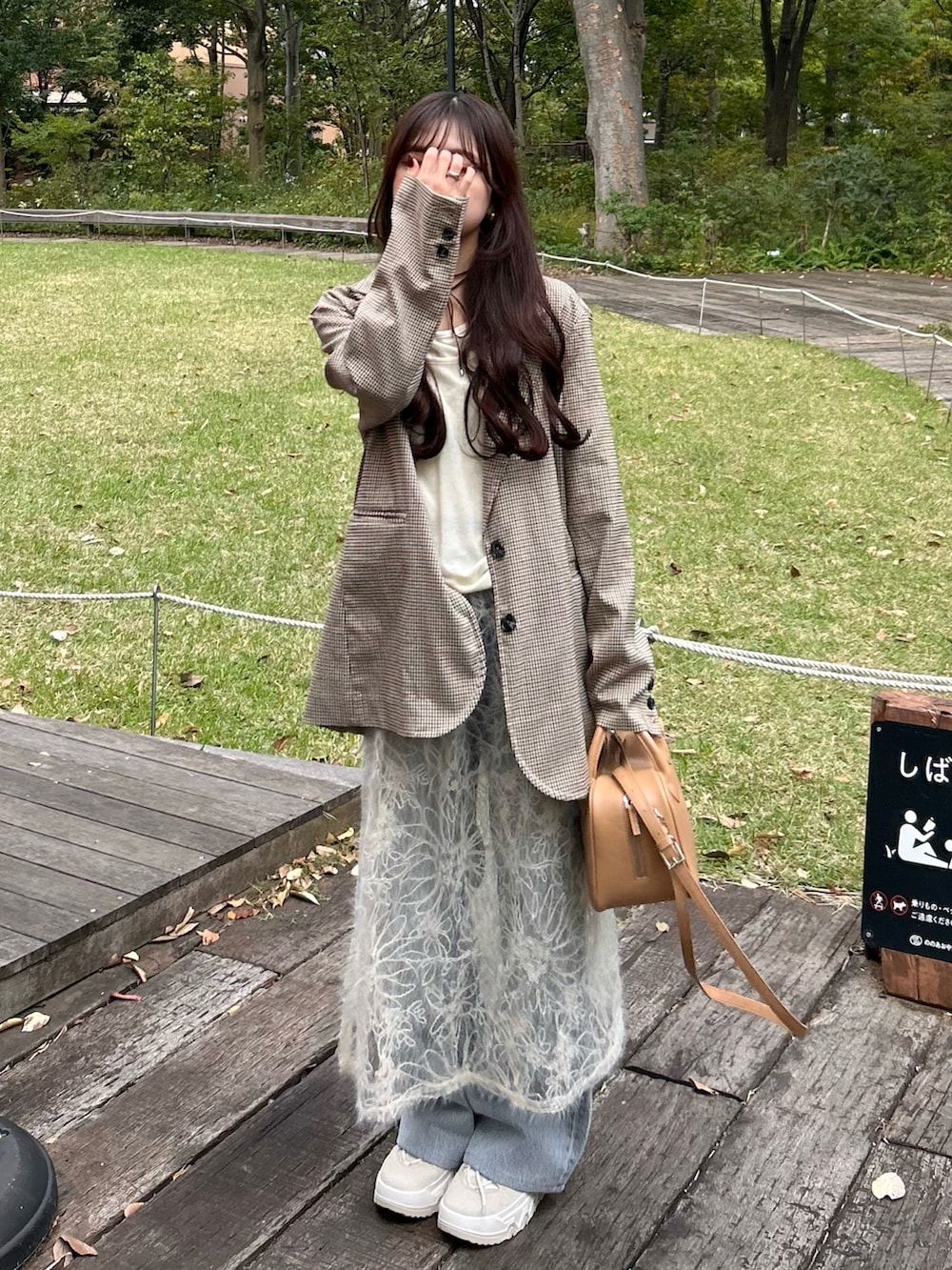 ベージュ系のテーラードジャケット、ブラウン系のスニーカー、ブルー系のデニムパンツを着用したレディースの秋コーディネートの3枚目の写真