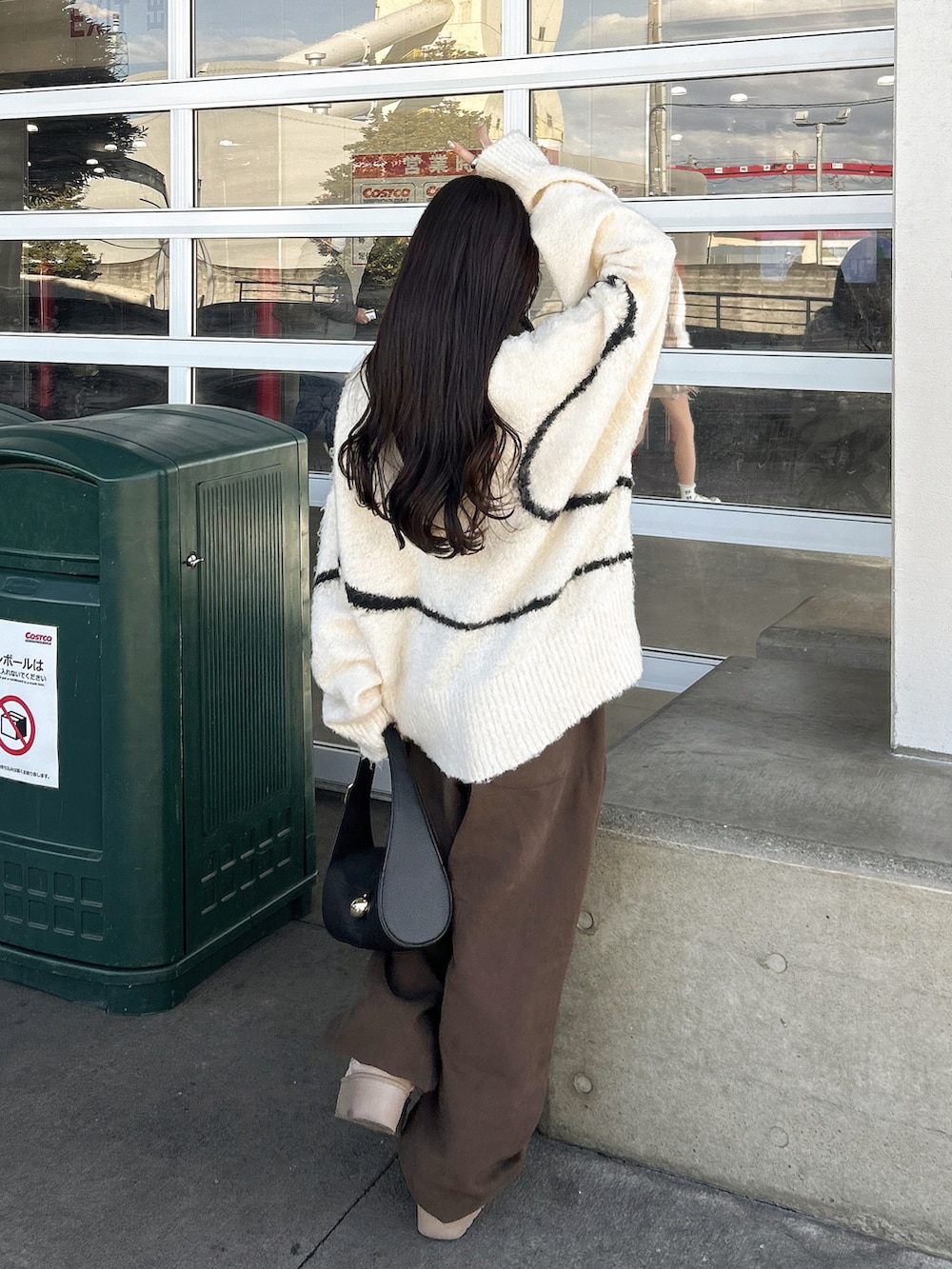 ブラウン系のスウェットパンツ、ホワイト系のニット/セーター、ブラック系のバッグを着用したレディースの冬コーディネートの2枚目の写真