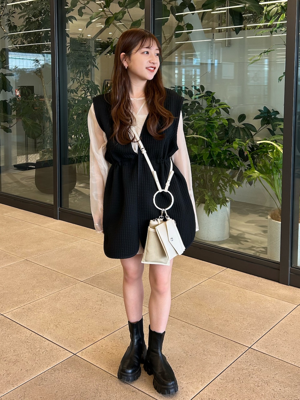 ブラック系のベスト、ベージュ系のシャツ/ブラウス、ベージュ系のショルダーバッグを着用したレディースの春コーディネートの2枚目の写真