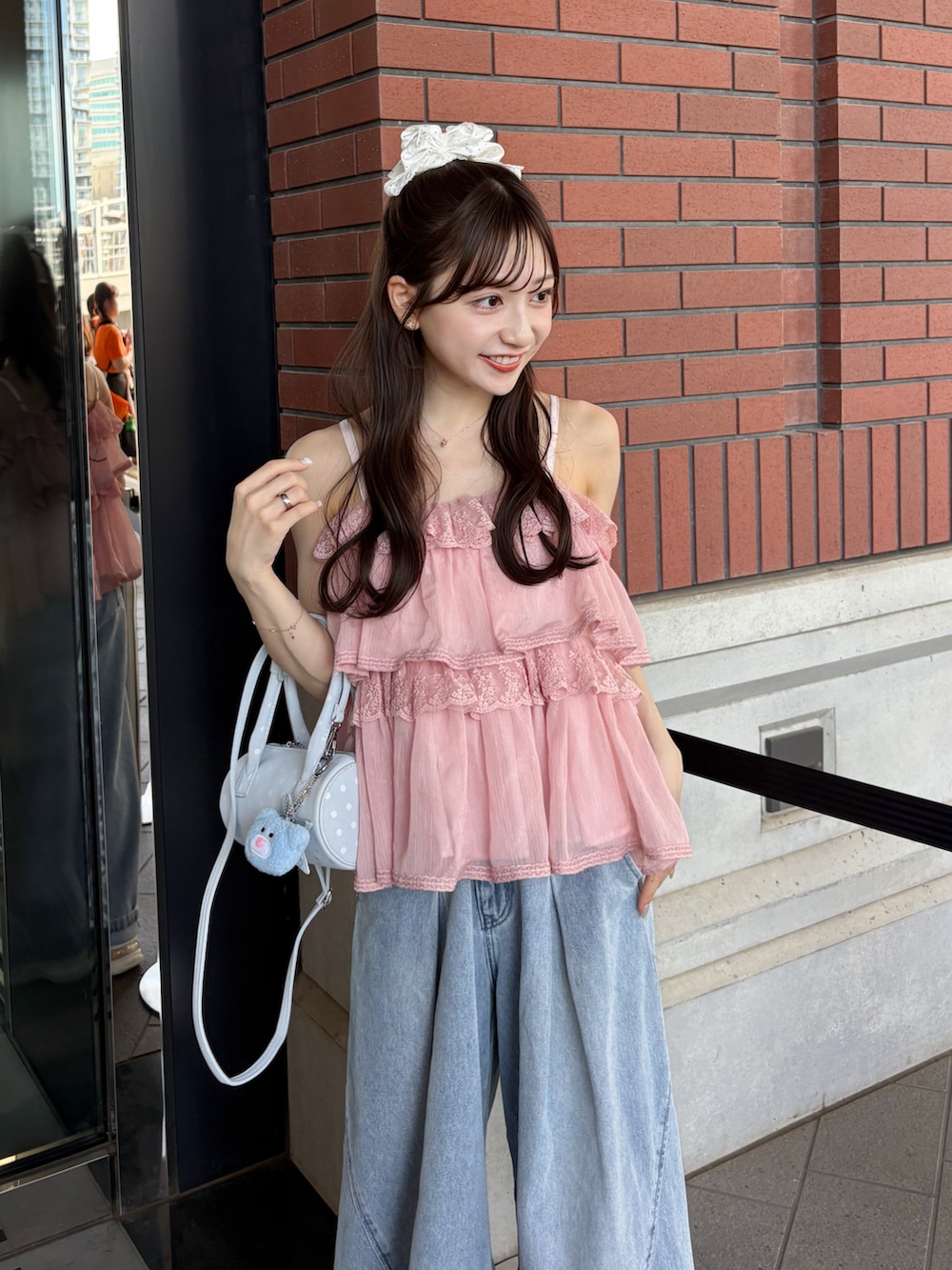 ブルー系のデニムパンツ、ホワイト系のトップス、ホワイト系のスニーカーを着用したレディースの夏コーディネートの3枚目の写真