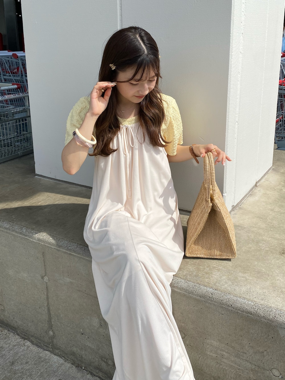 ベージュ系のトートバッグ、ホワイト系のワンピース、イエロー系のTシャツ/カットソーを着用したレディースの夏コーディネートの3枚目の写真