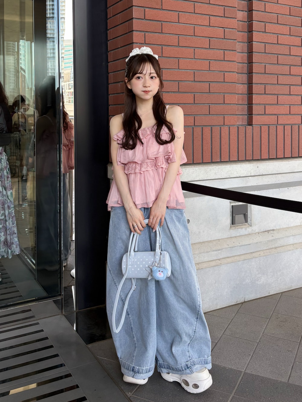 ブルー系のデニムパンツ、ホワイト系のトップス、ホワイト系のスニーカーを着用したレディースの夏コーディネートの2枚目の写真