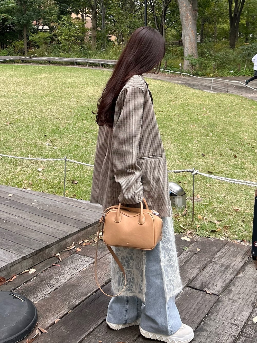 ベージュ系のテーラードジャケット、ブラウン系のスニーカー、ブルー系のデニムパンツを着用したレディースの秋コーディネートの2枚目の写真