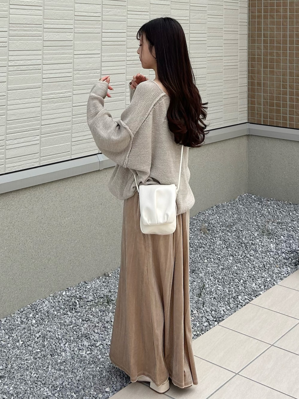 ホワイト系のショルダーバッグ、ベージュ系のニット/セーター、ホワイト系のワンピースを着用したレディースの秋コーディネートの2枚目の写真