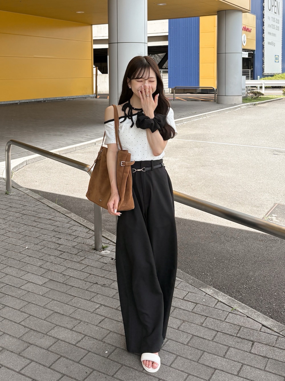 ホワイト系のサンダル、ブラック系のスラックス、ブラウン系のトートバッグを着用したレディースの夏コーディネートの3枚目の写真