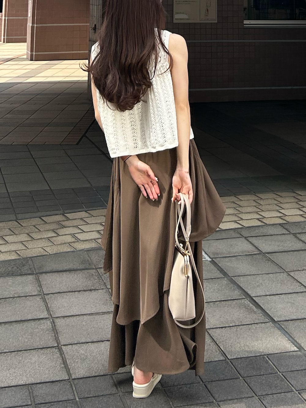 ホワイト系のベスト、ベージュ系のキャミソール、ブラウン系のスカートを着用したレディースの夏コーディネートの4枚目の写真