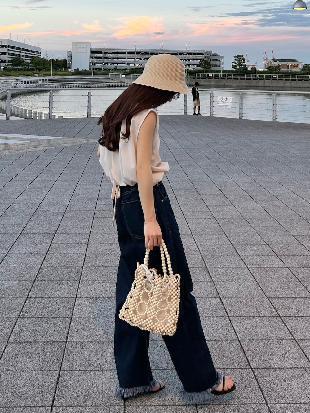 ホワイト系のハンドバッグ、ブルー系のデニムパンツ、ピンク系のシャツ/ブラウスを着用したレディースの夏コーディネートの2枚目の写真