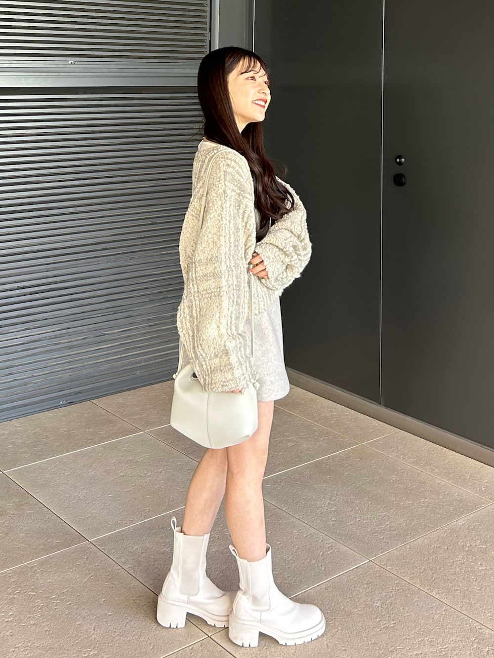 ホワイト系のブーツ、ホワイト系のショルダーバッグ、ホワイト系のカーディガン/ボレロを着用したレディースの冬コーディネートの4枚目の写真