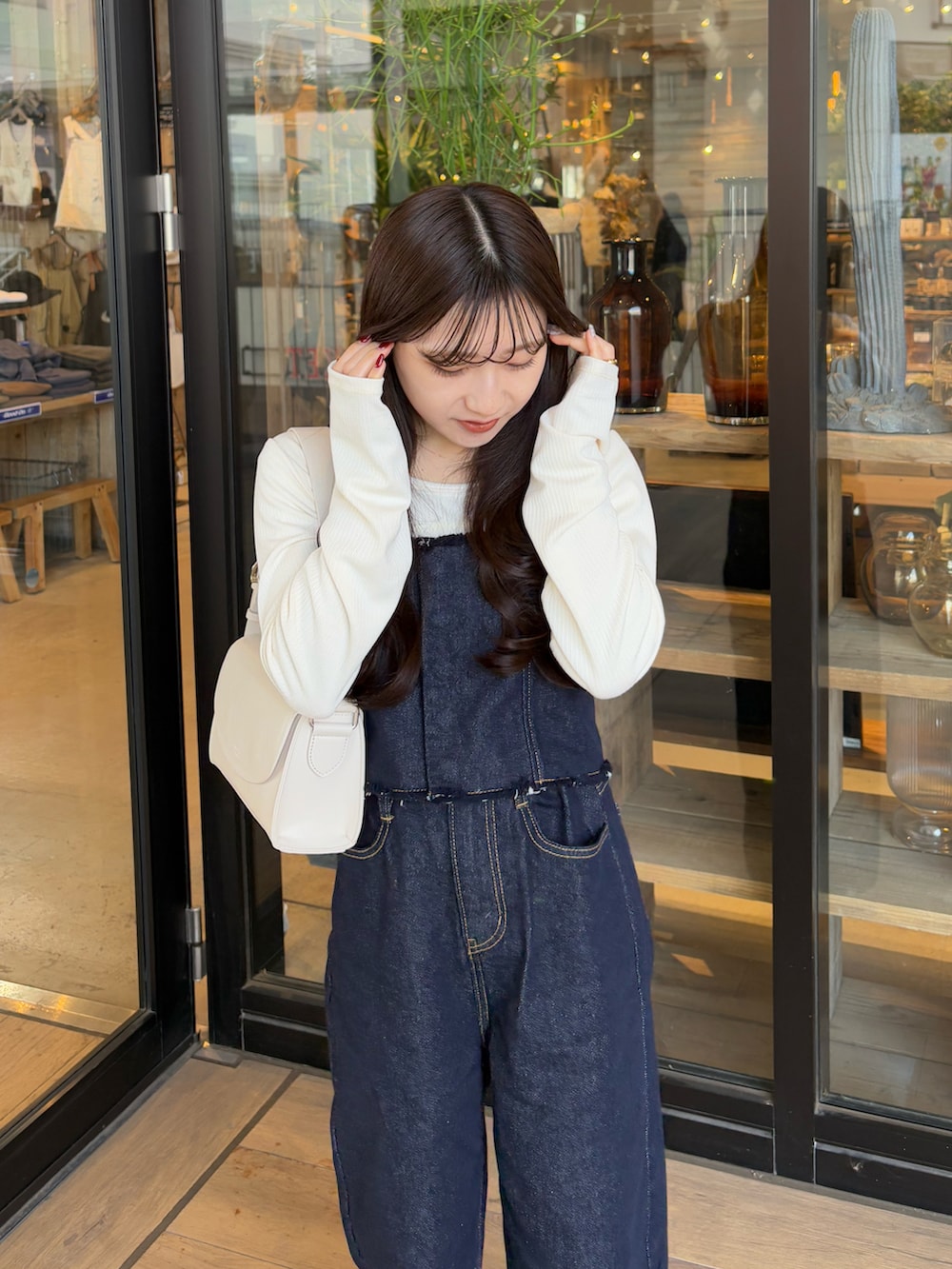 ブルー系のデニムパンツ、ブラウン系のブルゾン、ホワイト系のショルダーバッグを着用したレディースの冬コーディネートの4枚目の写真