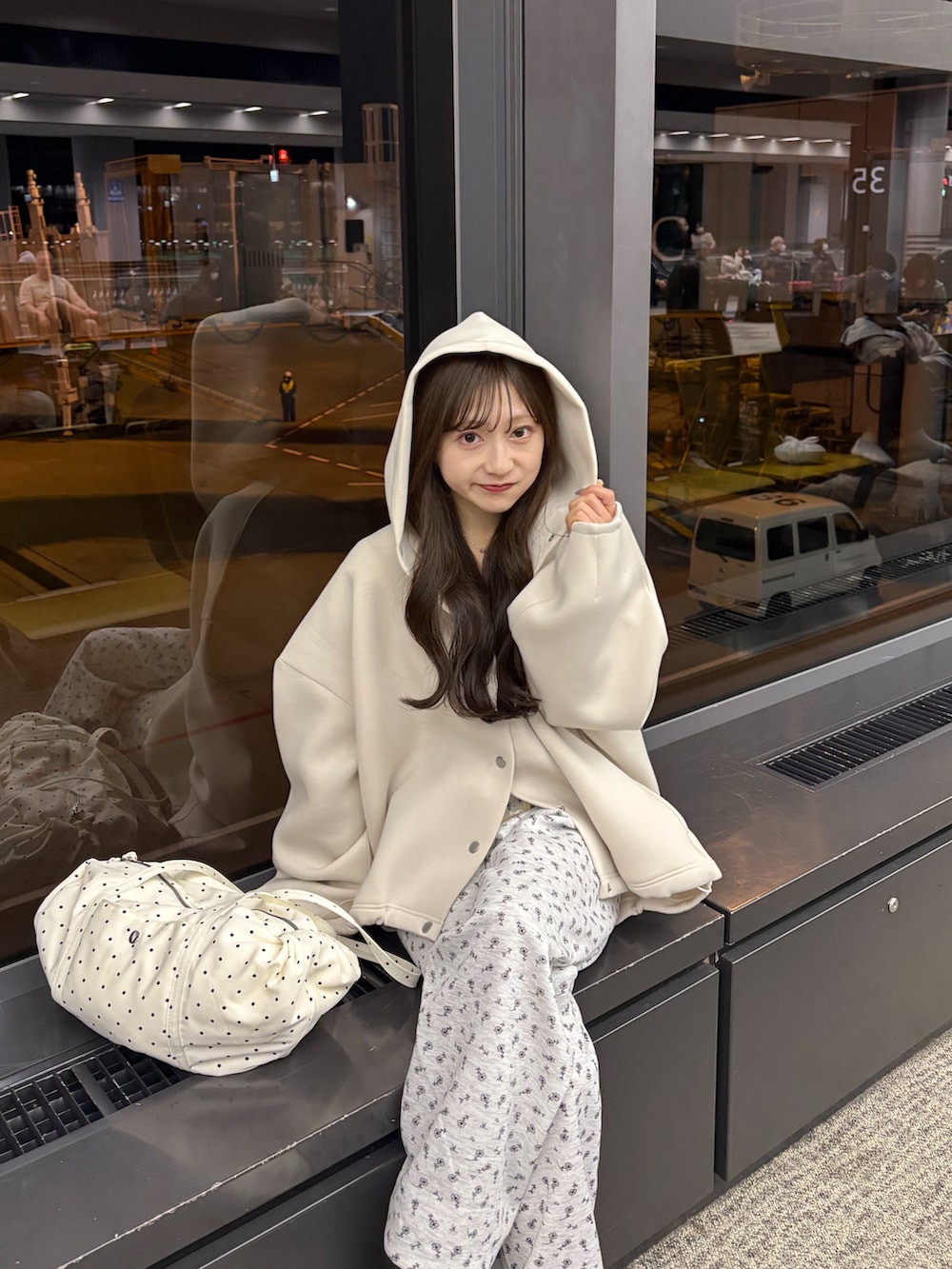 ホワイト系のブルゾン、グレー系のスウェットパンツ、ベージュ系のショルダーバッグを着用したレディースの春コーディネートの2枚目の写真