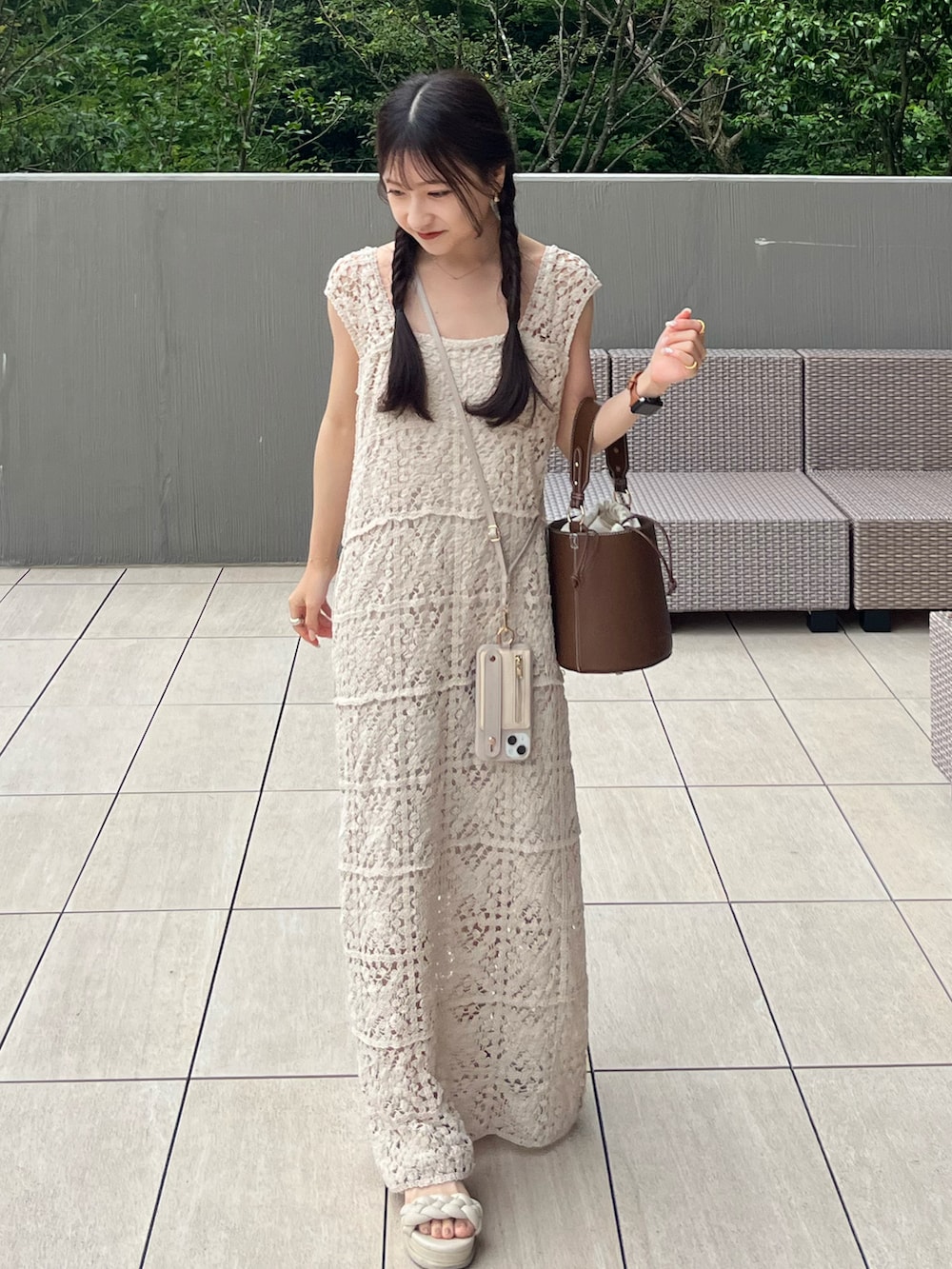ブラウン系のハンドバッグ、ホワイト系のワンピース、ホワイト系のサンダルを着用したレディースの夏コーディネートの2枚目の写真