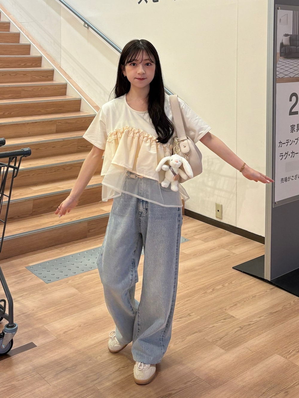 ベージュ系のTシャツ/カットソー、ベージュ系のハンドバッグ、ホワイト系のスニーカーを着用したレディースの夏コーディネートの2枚目の写真