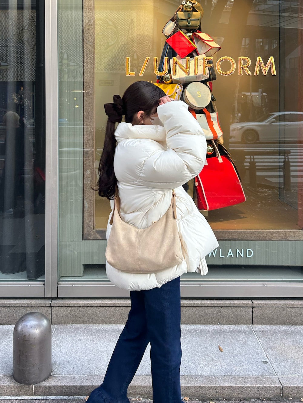 ブルー系のデニムパンツ、ホワイト系のダウンジャケット/コート、ベージュ系のショルダーバッグを着用したレディースの冬コーディネートの4枚目の写真