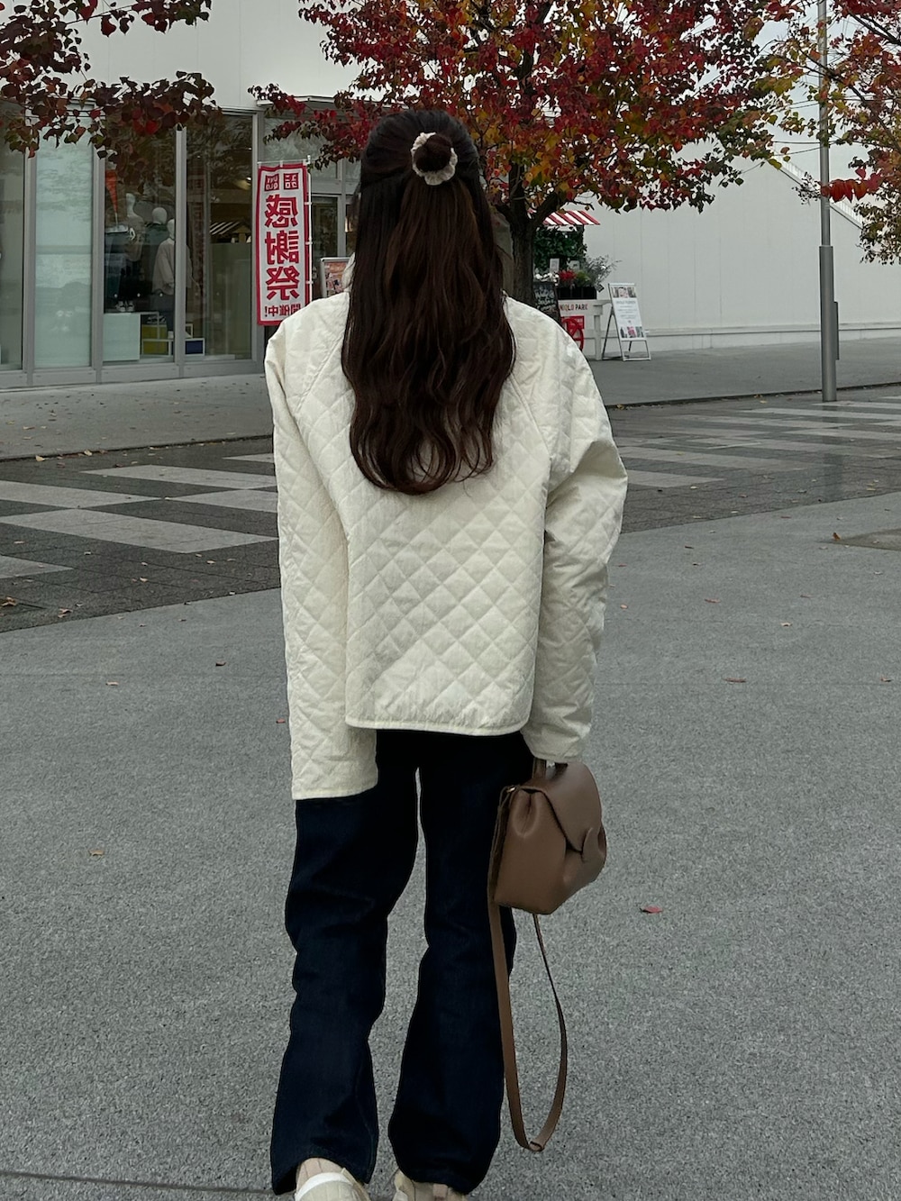 ブルー系のデニムパンツ、ブラウン系のバッグ、ホワイト系のジャケット/アウターを着用したレディースの秋コーディネートの3枚目の写真