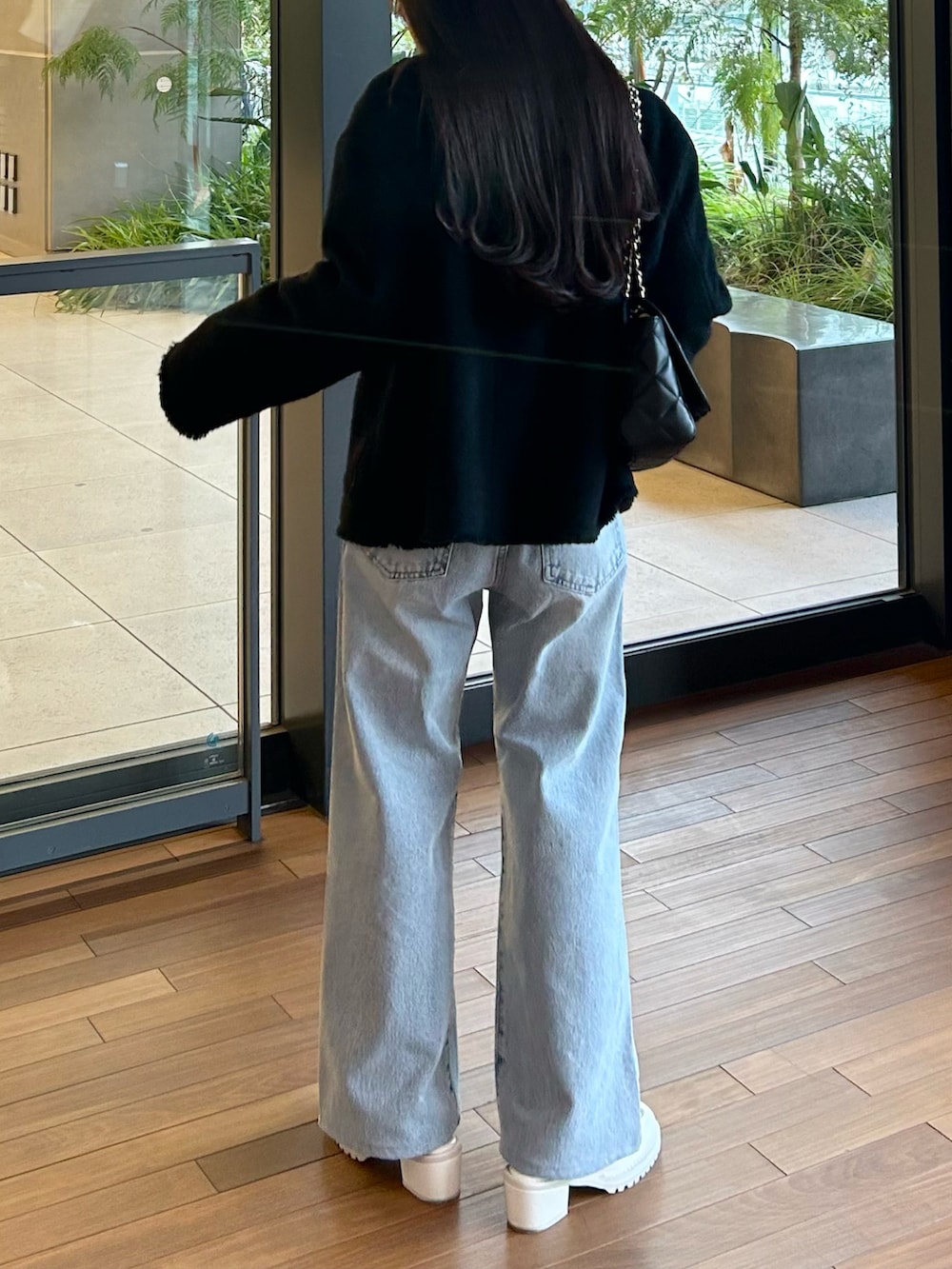 ブルー系のデニムパンツ、ブラック系のジャケット/アウター、ホワイト系のニット/セーターを着用したレディースの春コーディネートの4枚目の写真