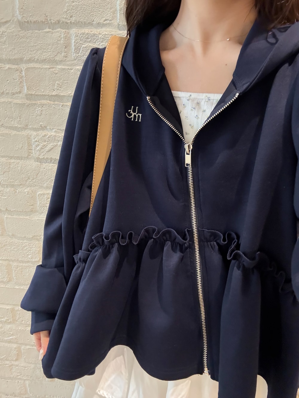 ベージュ系のブーツ、ブラウン系のパーカー、ホワイト系のスカートを着用したレディースの秋コーディネートの3枚目の写真