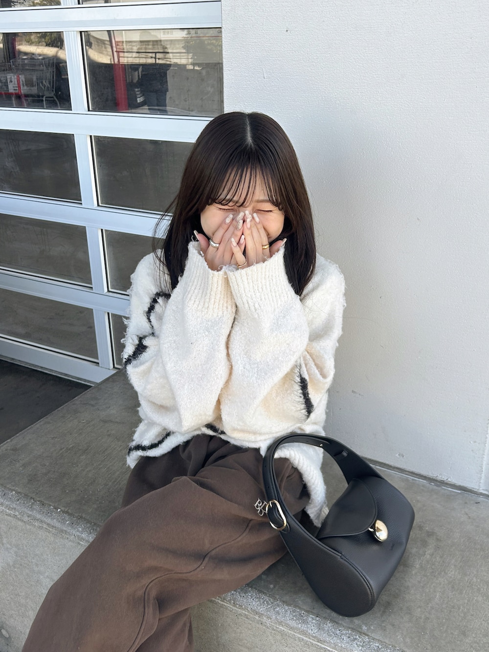 ブラウン系のスウェットパンツ、ホワイト系のニット/セーター、ブラック系のバッグを着用したレディースの冬コーディネートの4枚目の写真