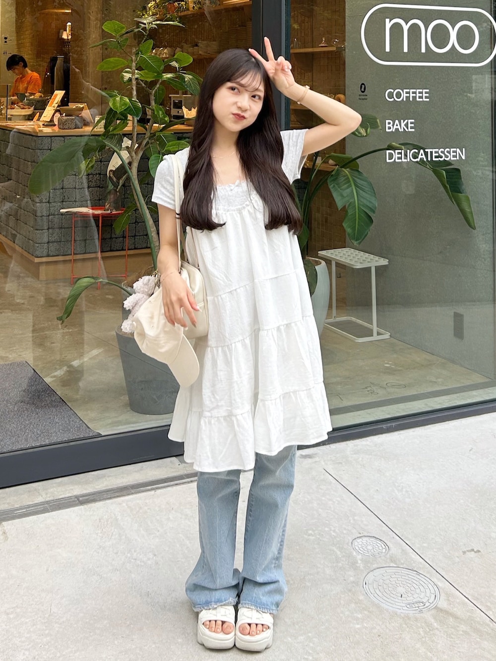 ブルー系のデニムパンツ、ホワイト系のワンピース、ホワイト系のショルダーバッグを着用したレディースの夏コーディネートの4枚目の写真