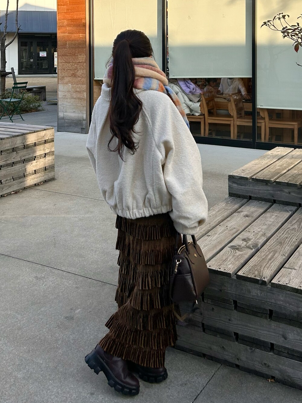 ブラウン系のバッグ、ブラウン系のスカート、ブラウン系のブーツを着用したレディースの冬コーディネートの4枚目の写真