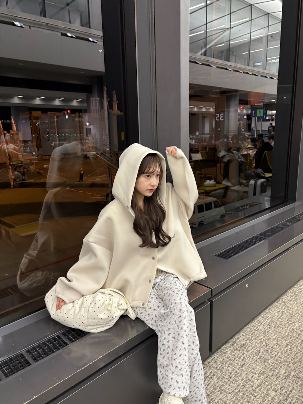 ホワイト系のブルゾン、グレー系のスウェットパンツ、ベージュ系のショルダーバッグを着用したレディースの春コーディネートの4枚目の写真