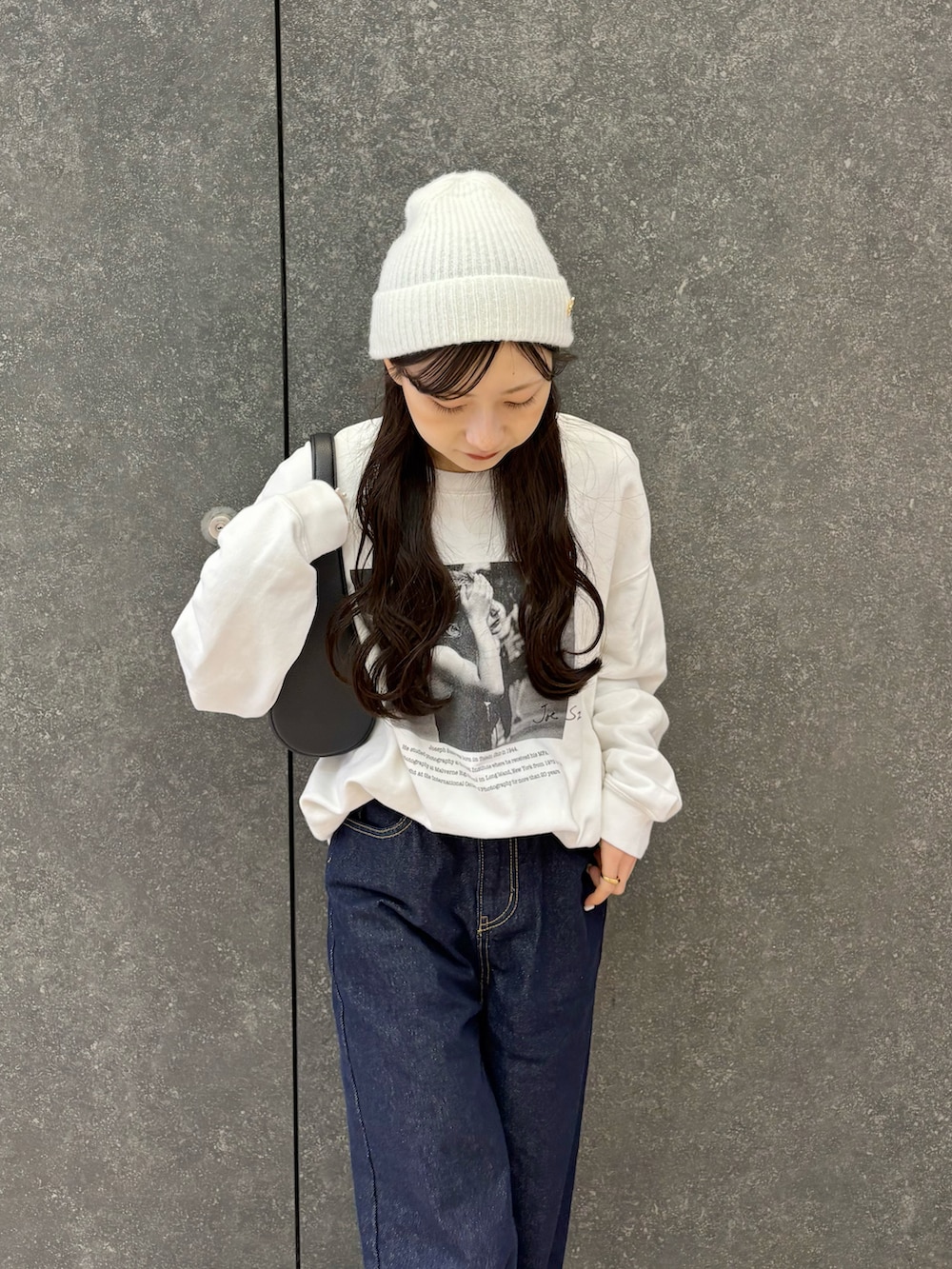 ホワイト系のスウェット、ブルー系のデニムパンツ、ブラック系のバッグを着用したレディースの春コーディネートの3枚目の写真