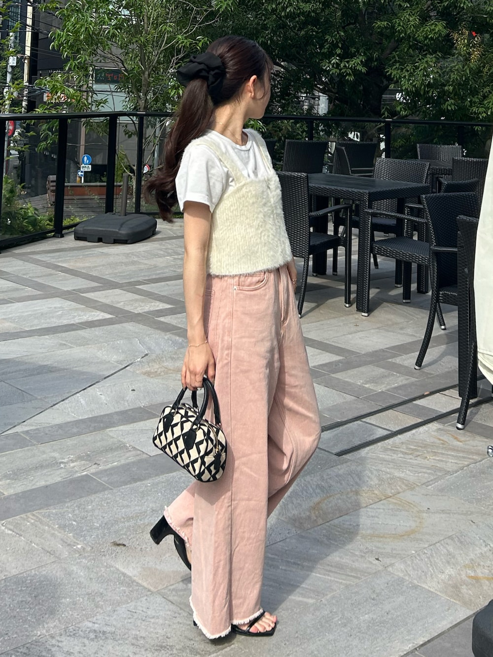 ブラック系のバッグ、ピンク系のデニムパンツ、ホワイト系のベストを着用したレディースの秋コーディネートの2枚目の写真