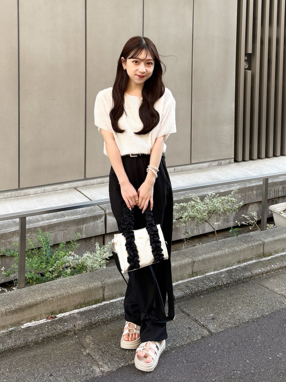 ブラック系のスラックス、ベージュ系のサンダル、ホワイト系のTシャツ/カットソーを着用したレディースの夏コーディネートの3枚目の写真