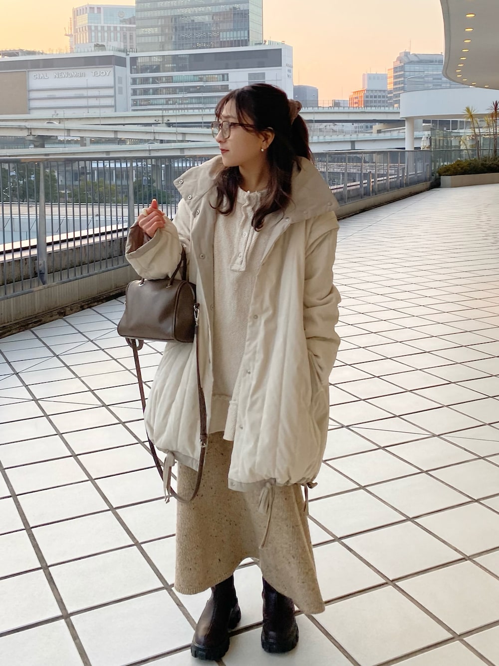 ホワイト系のダウンジャケット/コート、ベージュ系のショルダーバッグ、ホワイト系のTシャツ/カットソーを着用したレディースの冬コーディネートの2枚目の写真