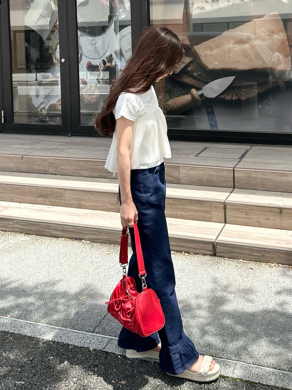 ブルー系のデニムパンツ、レッド系のショルダーバッグ、ホワイト系のTシャツ/カットソーを着用したレディースの夏コーディネートの2枚目の写真