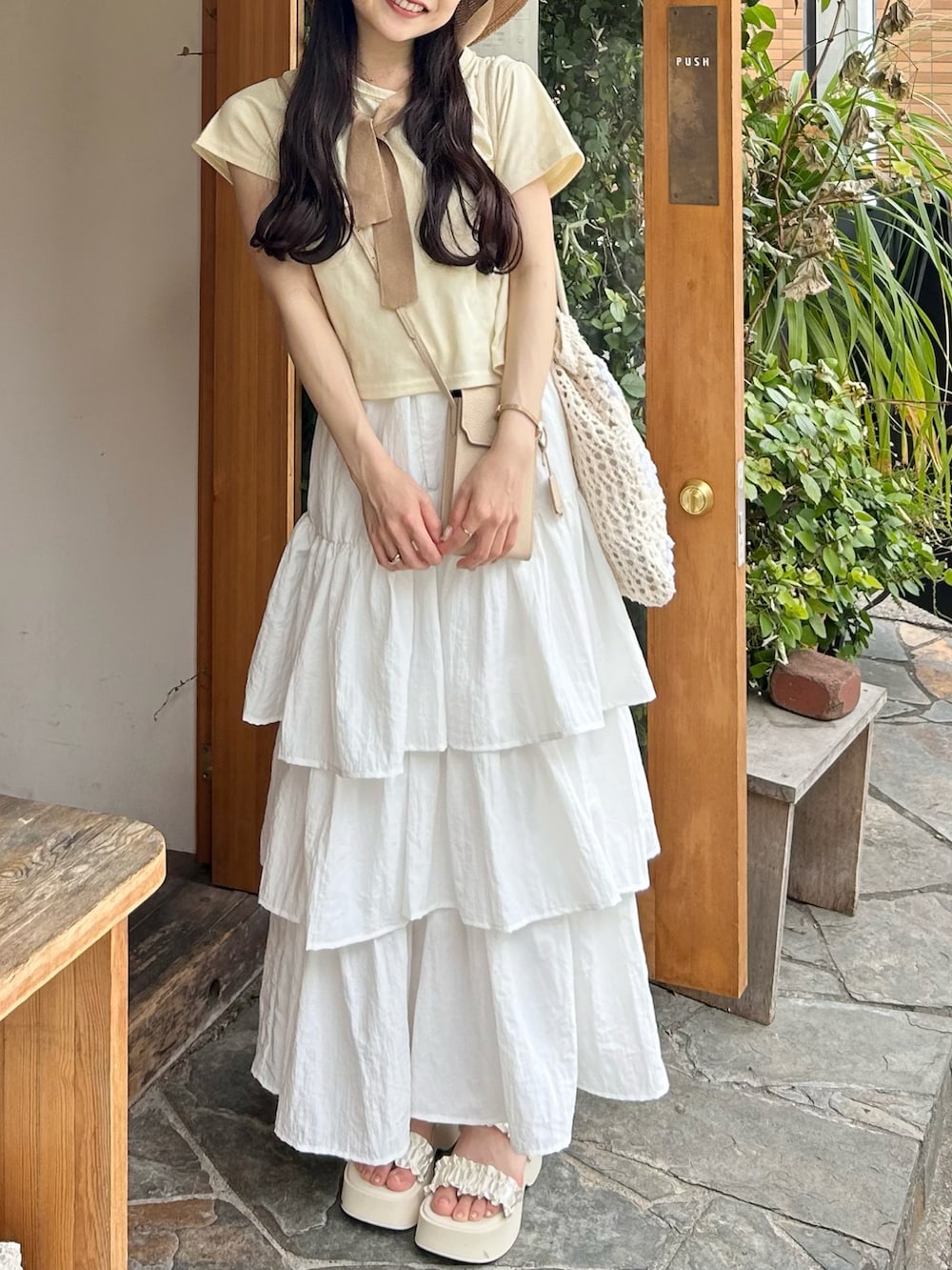 イエロー系のTシャツ/カットソー、ホワイト系のスカート、ホワイト系のサンダルを着用したレディースの夏コーディネートの4枚目の写真