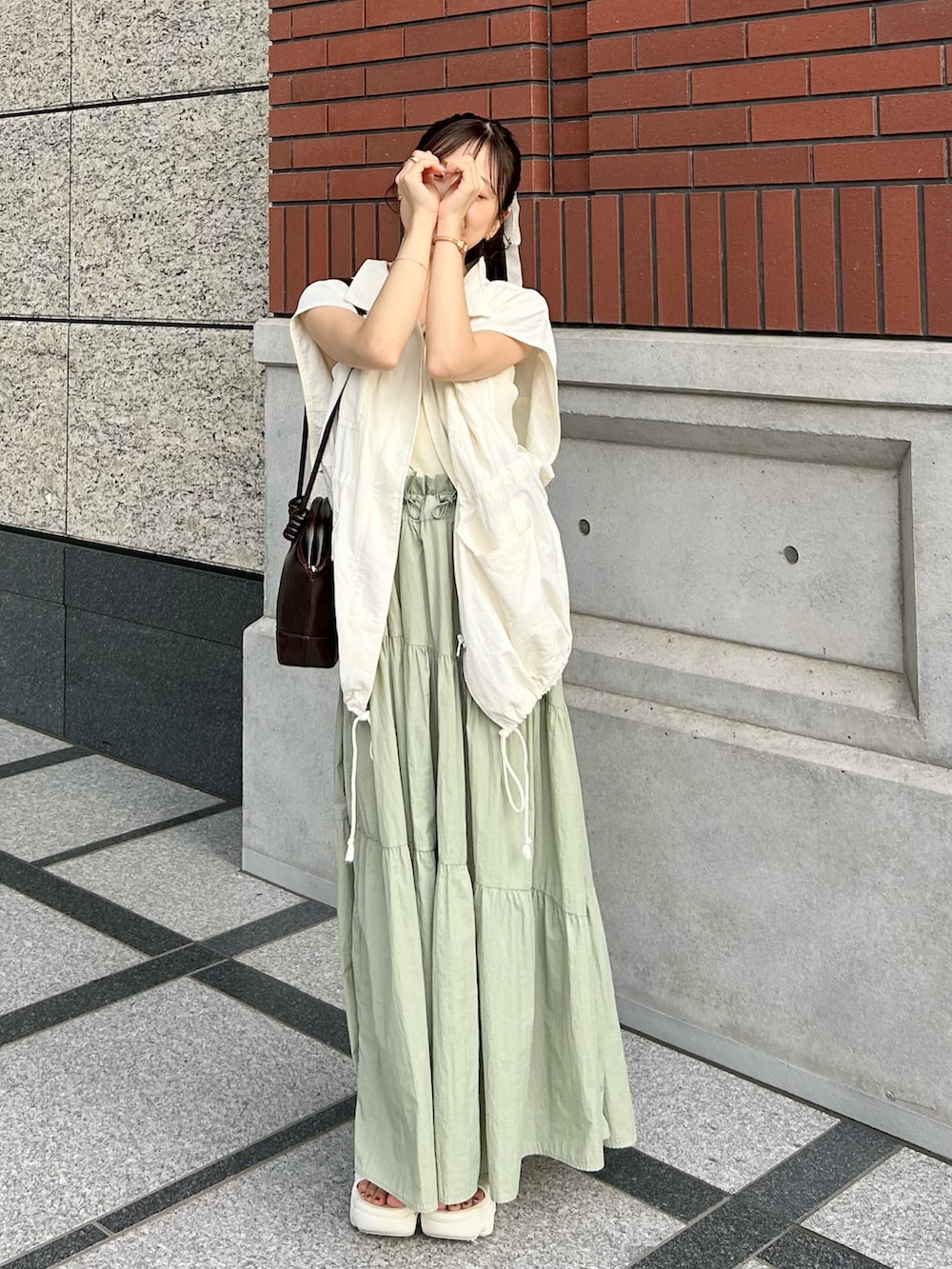 ブラウン系のショルダーバッグ、ホワイト系のミリタリージャケット、ホワイト系のキャミソールを着用したレディースの秋コーディネートの3枚目の写真