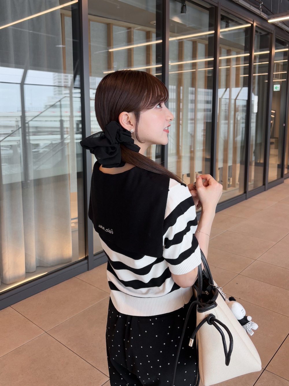 ブラック系のパンツ、グレー系のニット/セーター、ホワイト系のトートバッグを着用したレディースの夏コーディネートの2枚目の写真