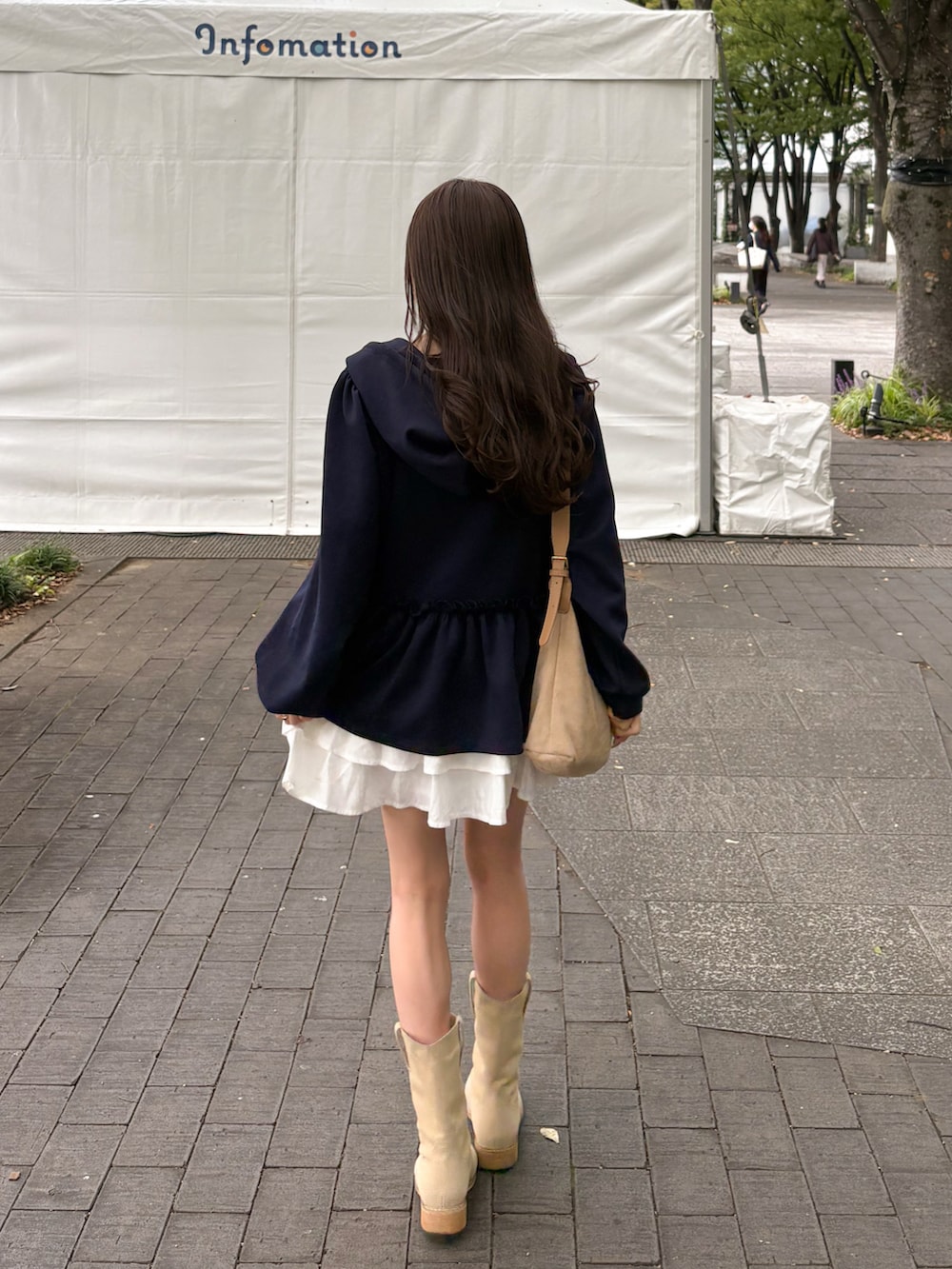 ベージュ系のブーツ、ブラウン系のパーカー、ホワイト系のスカートを着用したレディースの秋コーディネートの4枚目の写真