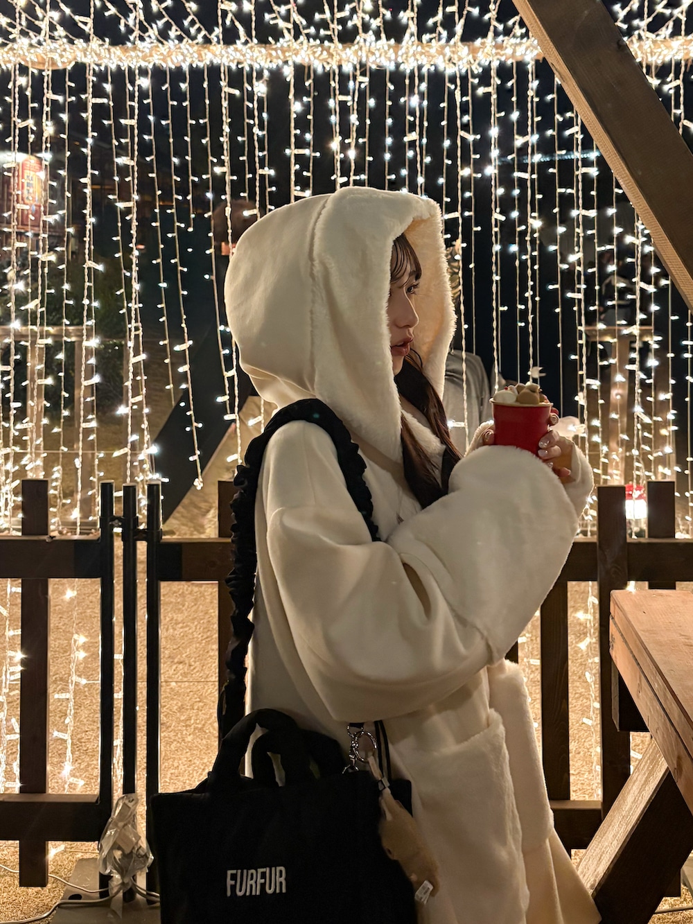 ブラック系のショルダーバッグ、ホワイト系のジャケット/アウター、ブラック系のサンダルを着用したレディースの冬コーディネートの4枚目の写真