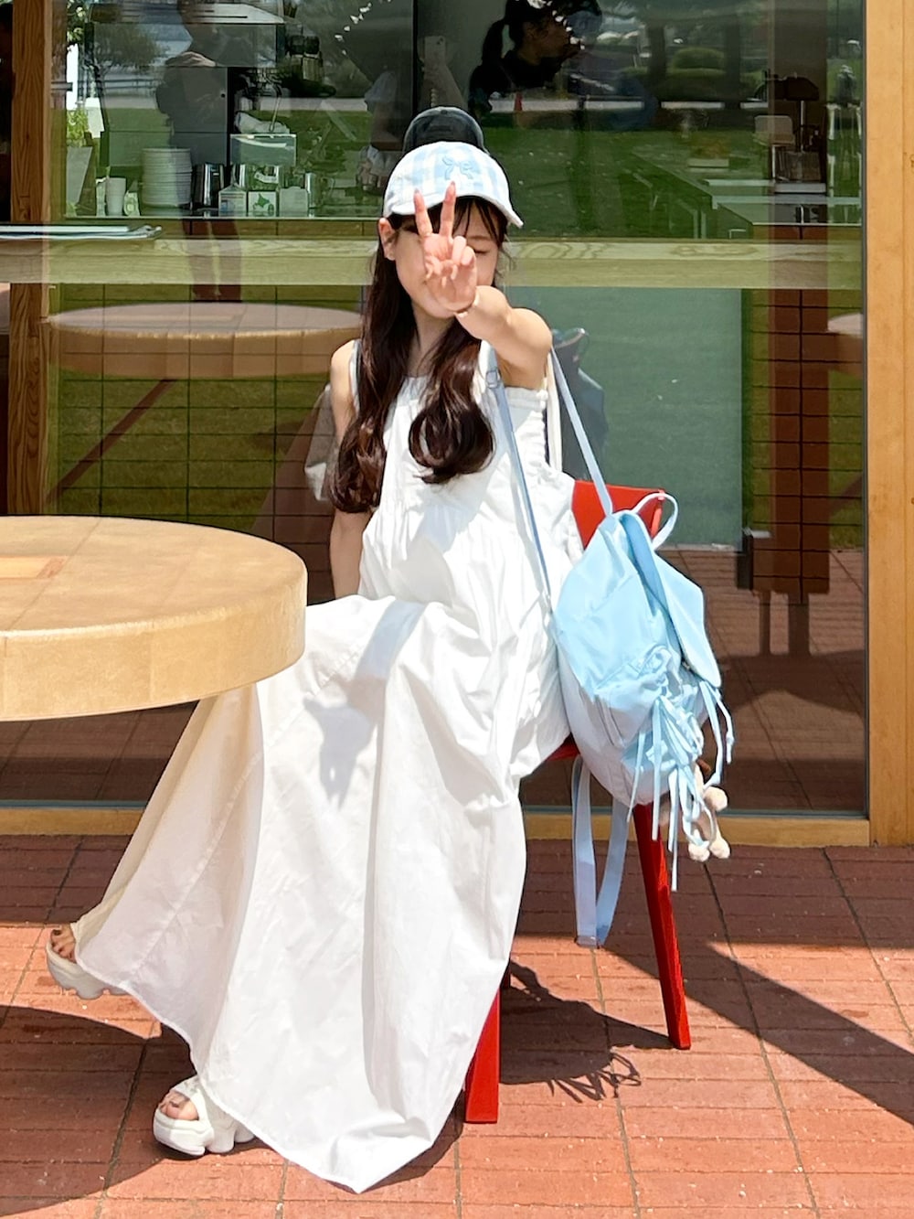 ホワイト系のワンピース、ブルー系のバックパック/リュック、ベージュ系のサンダルを着用したレディースの夏コーディネートの3枚目の写真