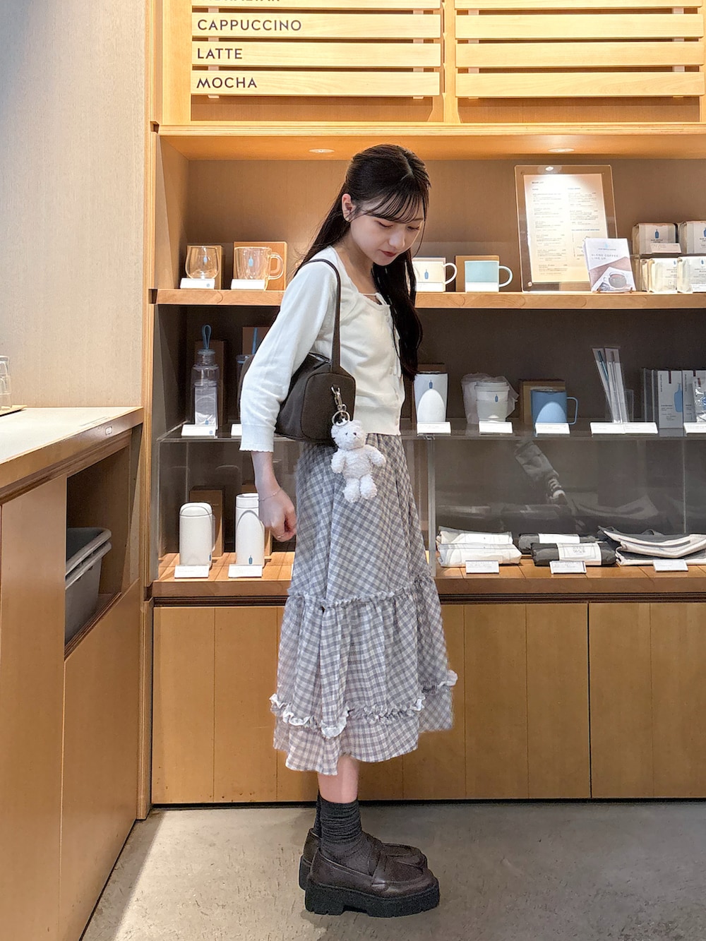 ホワイト系のカーディガン/ボレロ、ベージュ系のスカート、ブラウン系のショルダーバッグを着用したレディースの秋コーディネートの2枚目の写真