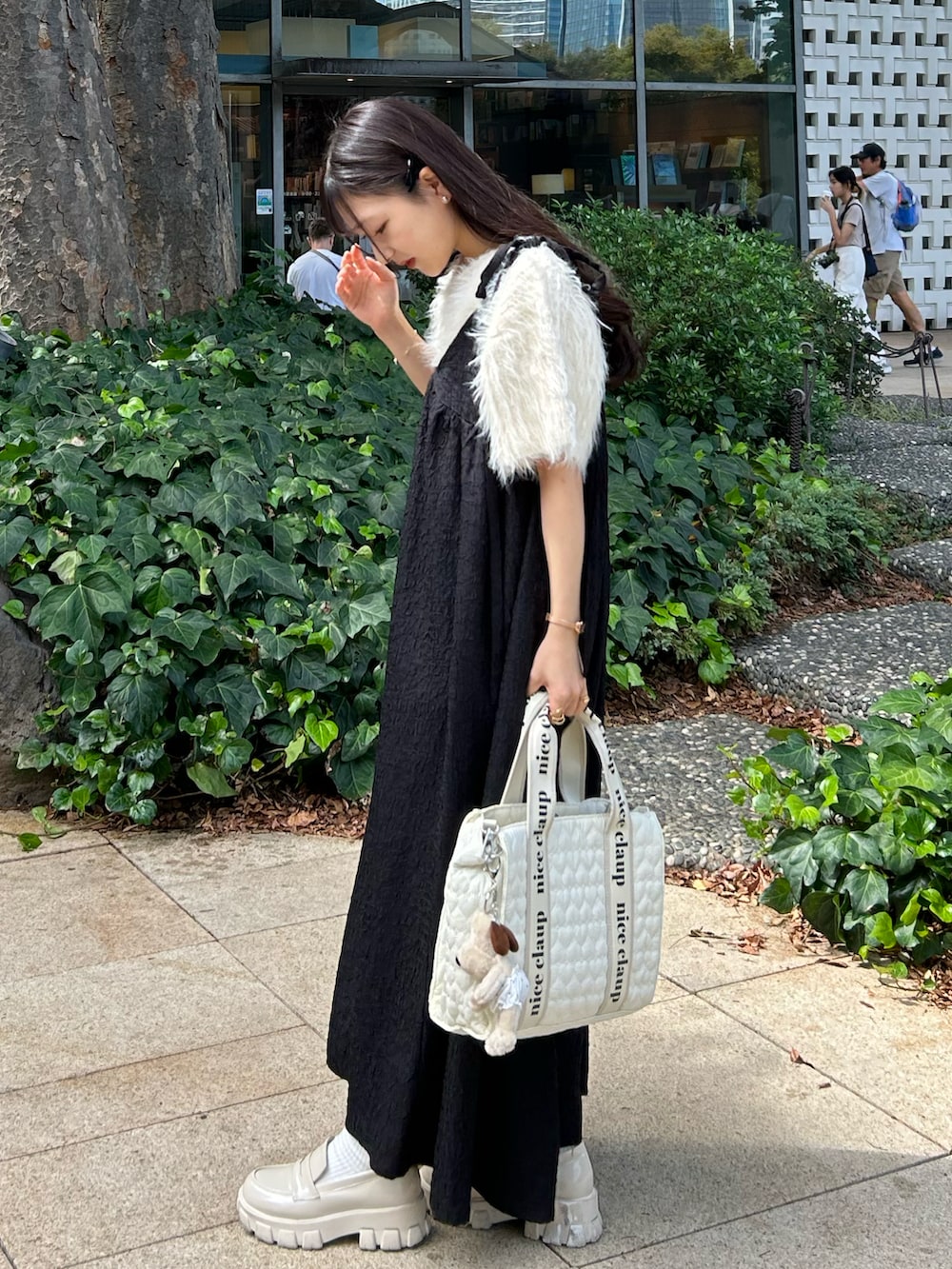 ホワイト系のトートバッグ、ブラック系のワンピースを着用したレディースの秋コーディネートの3枚目の写真