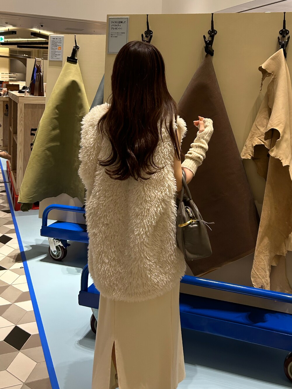 グレー系のショルダーバッグ、ホワイト系のワンピース、ホワイト系のダウンベストを着用したレディースの秋コーディネートの4枚目の写真