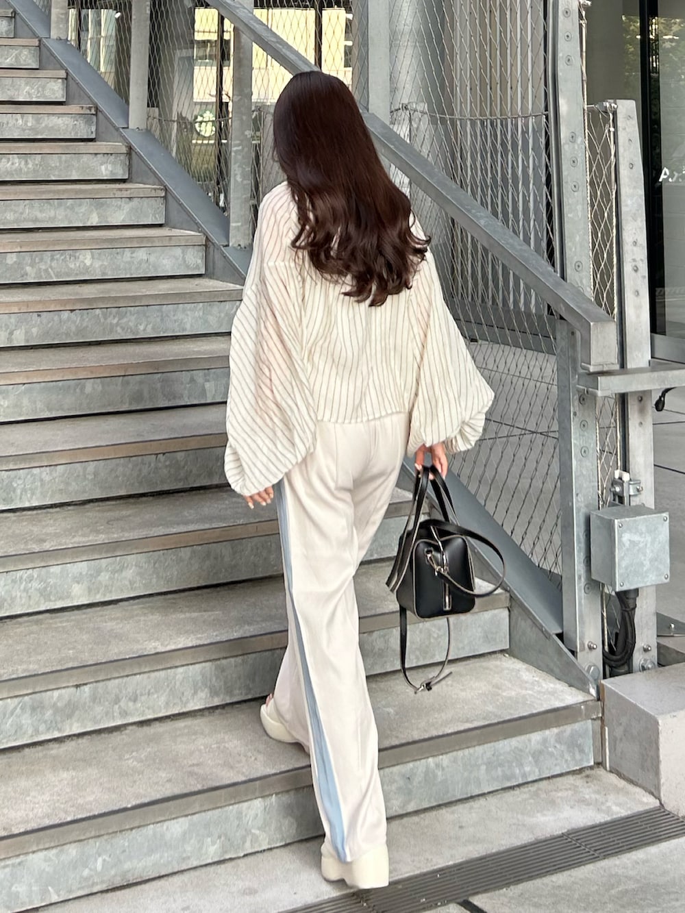 ブラック系のトートバッグ、ホワイト系のその他パンツ、ホワイト系のサンダルを着用したレディースの夏コーディネートの3枚目の写真