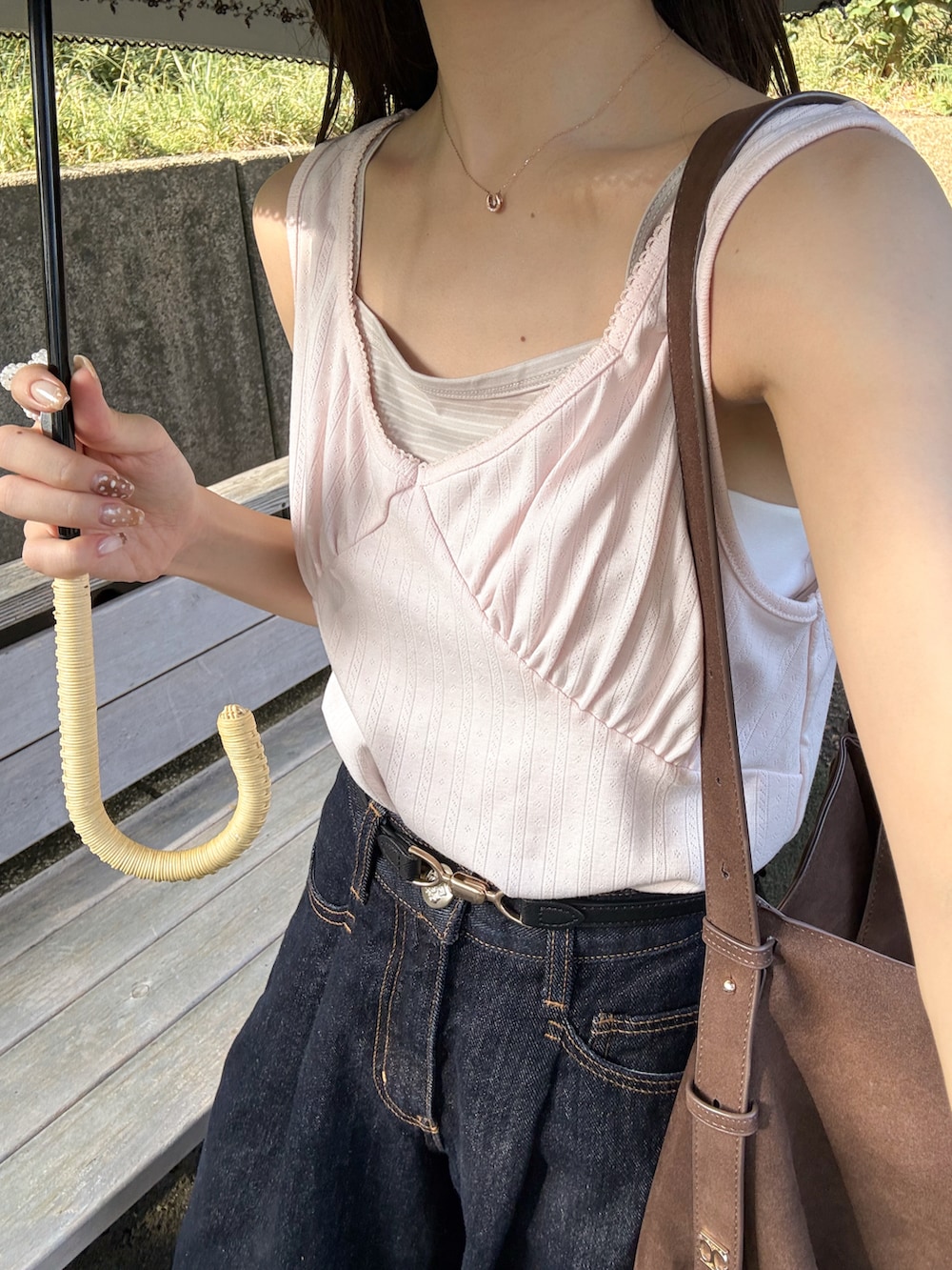ピンク系のタンクトップ、ブルー系のデニムパンツ、ブラウン系のトートバッグを着用したレディースの秋コーディネートの5枚目の写真