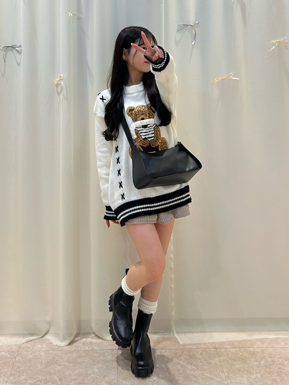 ホワイト系のニット/セーター、ブラック系のショルダーバッグ、ベージュ系のパンツを着用したレディースの秋コーディネートの3枚目の写真