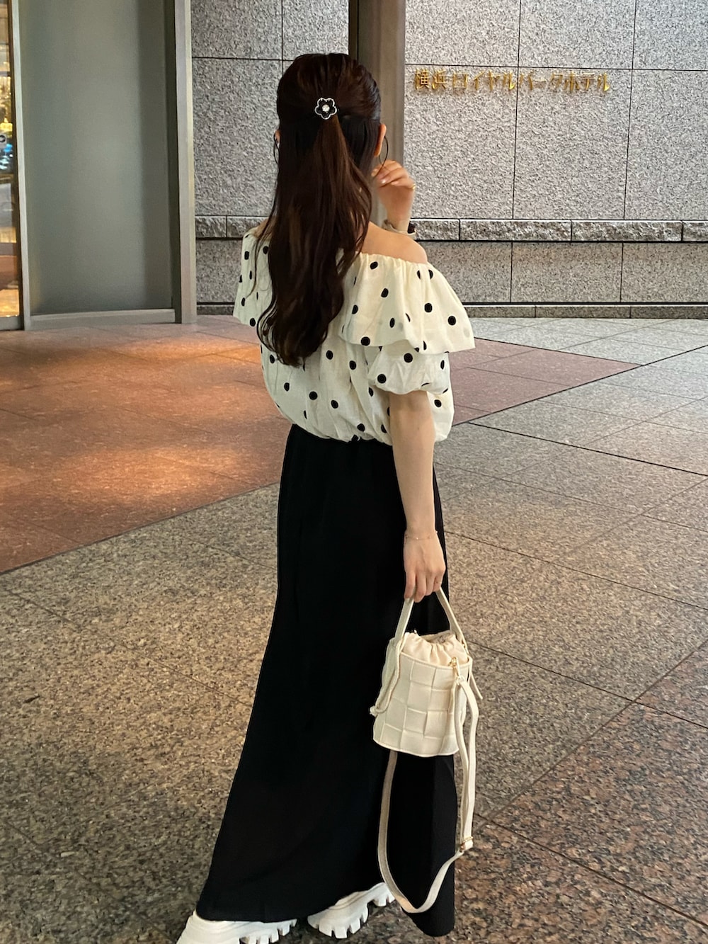 ホワイト系のトップス、ブラック系のスカート、ホワイト系のバッグを着用したレディースの夏コーディネートの2枚目の写真