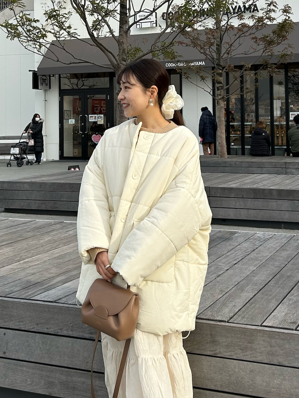 ブラウン系のバッグ、ベージュ系のニット/セーター、ホワイト系のダウンジャケット/コートを着用したレディースの冬コーディネートの3枚目の写真