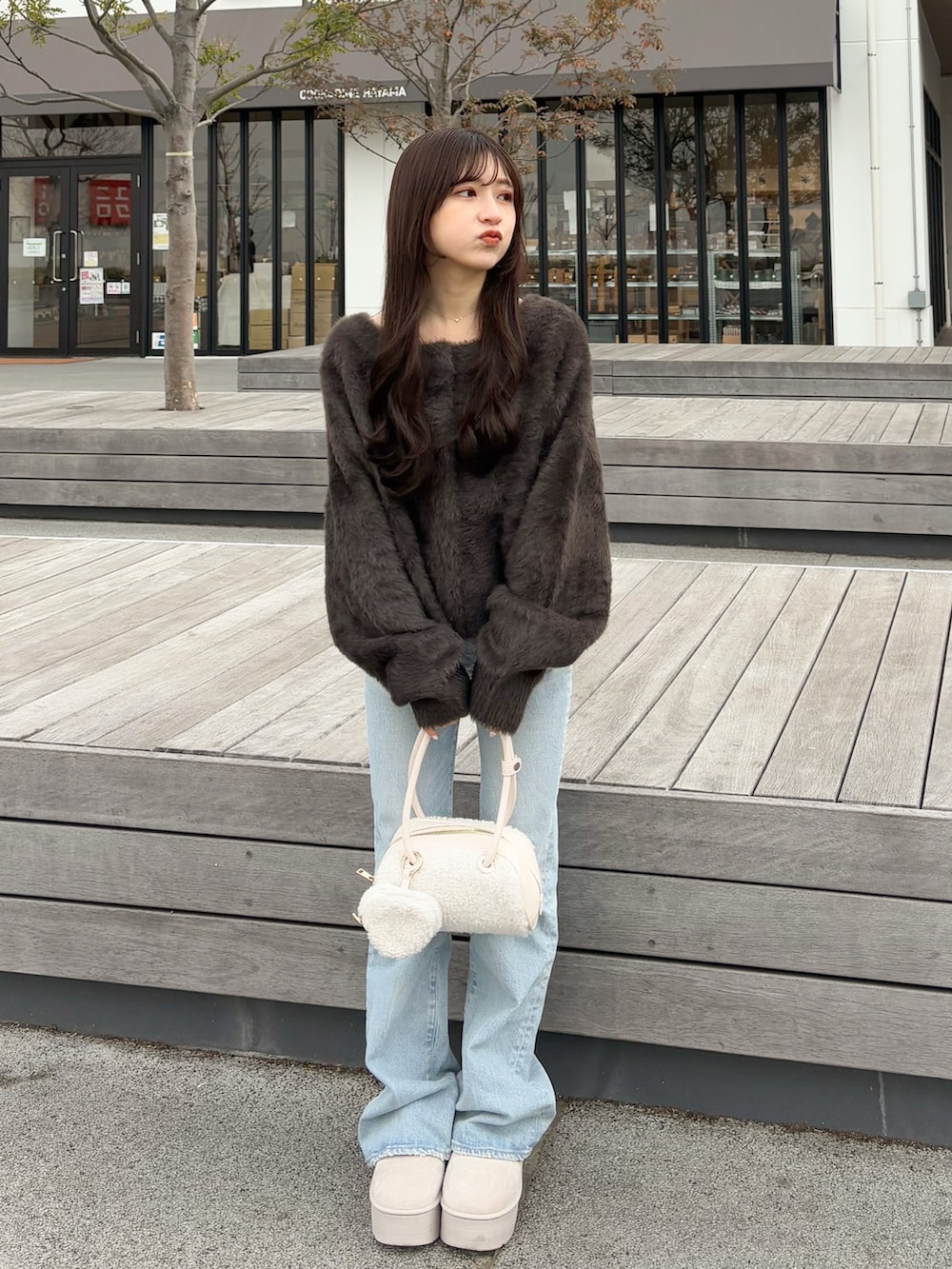 ブラウン系のカーディガン/ボレロ、ブルー系のデニムパンツ、ホワイト系のボストンバッグを着用したレディースの春コーディネートの3枚目の写真